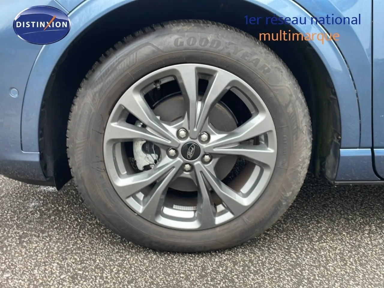 Gros plan sur la roue avant droite du Ford Kuga 2024 bleu Vapor Metal avec jante alliage et logo Ford central.