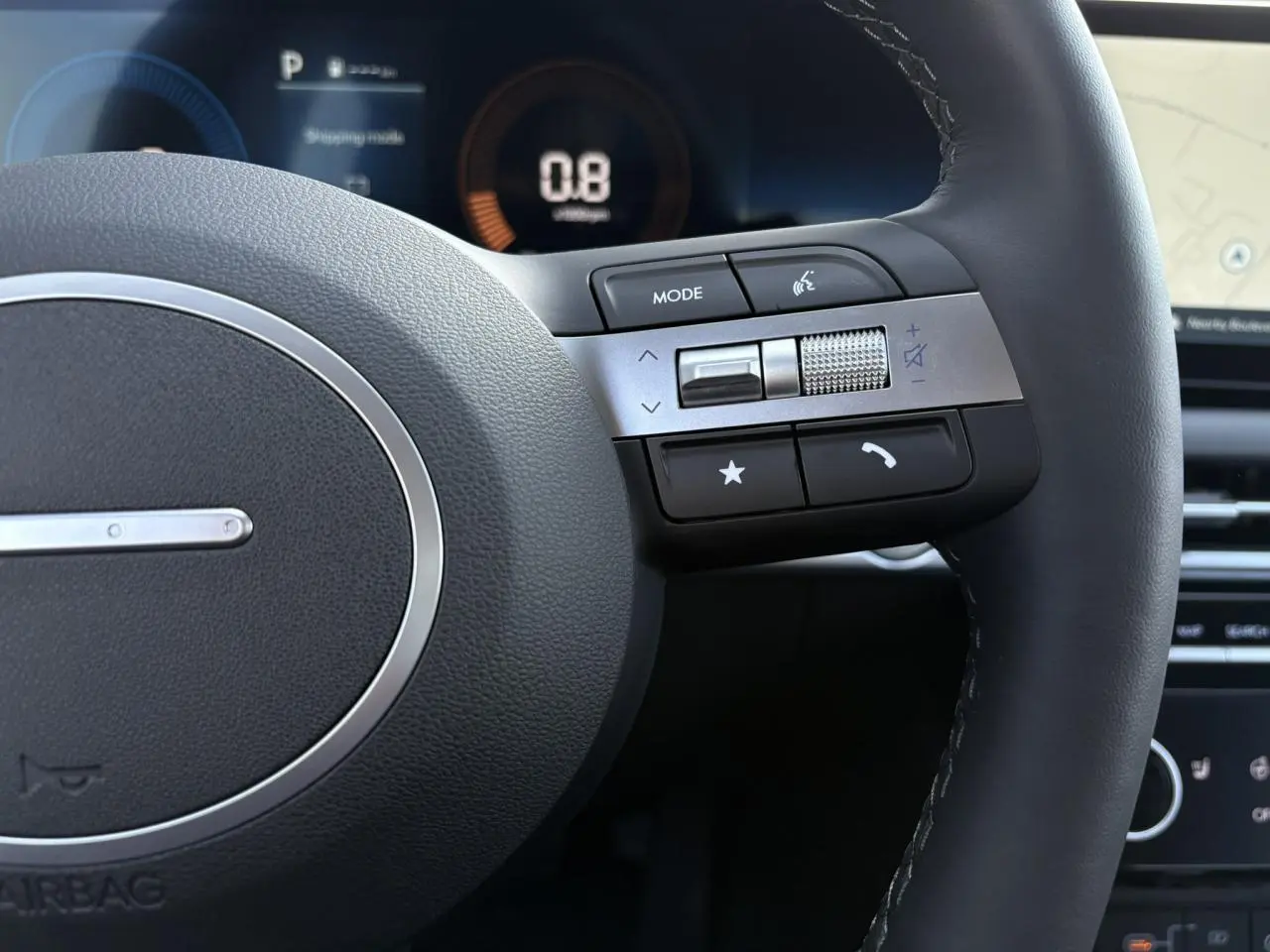 Gros plan sur le volant cuir noir du Hyundai Tucson 2025, avec commandes multimédia et tableau de bord numérique en arrière-plan.