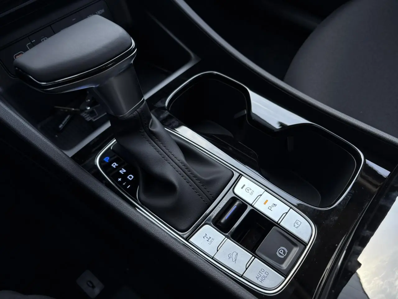 Gros plan sur la console centrale noire du Hyundai Tucson 2025 avec levier de vitesses automatique et commandes intégrées.