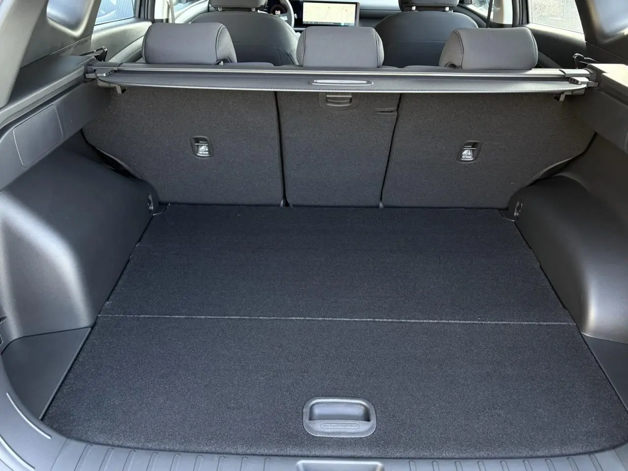 Coffre spacieux vu de l'intérieur arrière du Hyundai Tucson 2025, avec cache-bagages et revêtement noir.