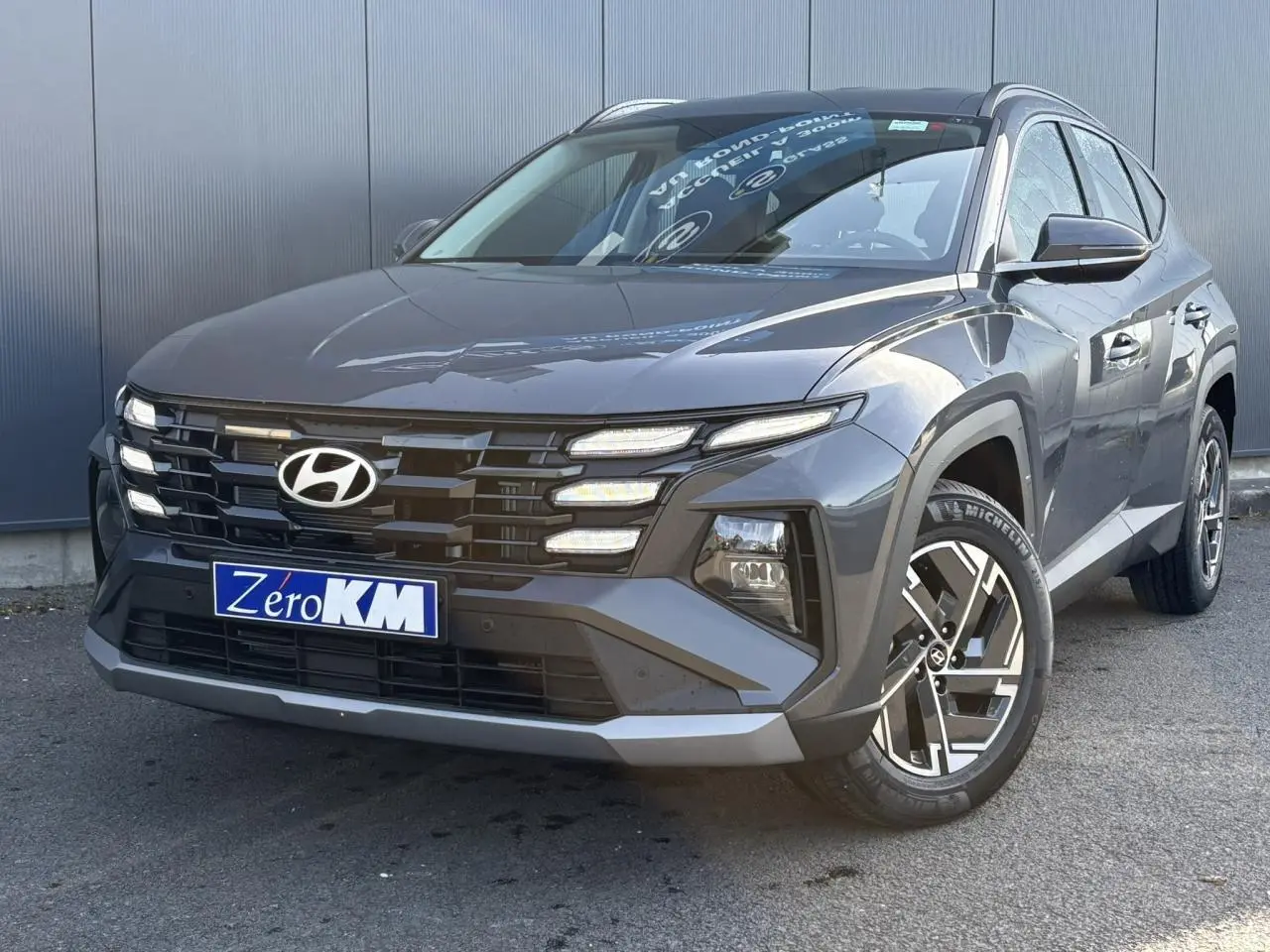 Hyundai Tucson 2025 Ecotronic Gray en 3/4 avant droit avec calandre noire et jantes alliage 17 pouces.