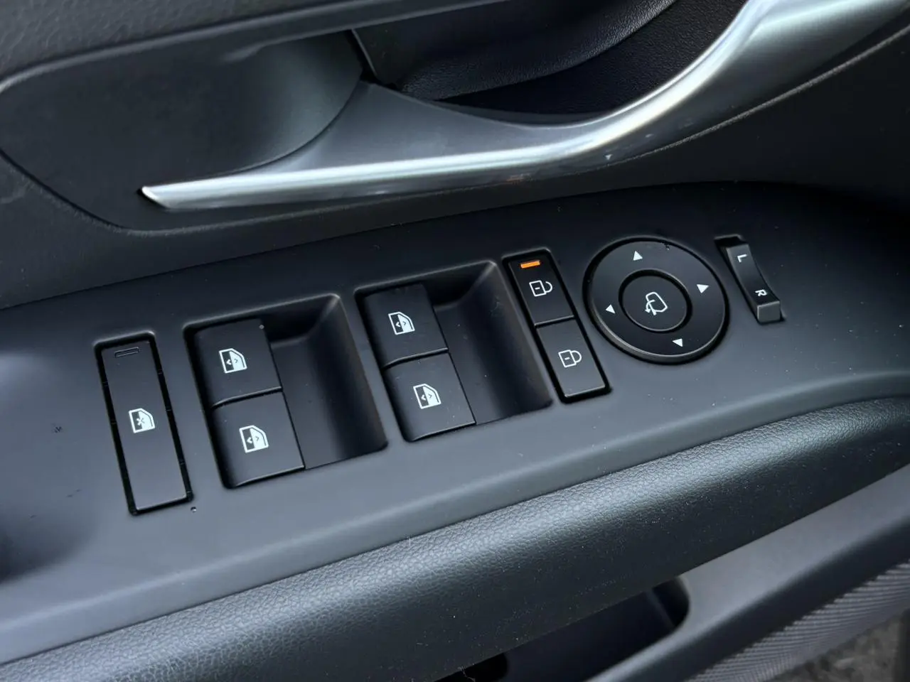 Gros plan sur les commandes de vitres et rétroviseurs côté conducteur du Hyundai Tucson 2025 en Ecotronic Gray.