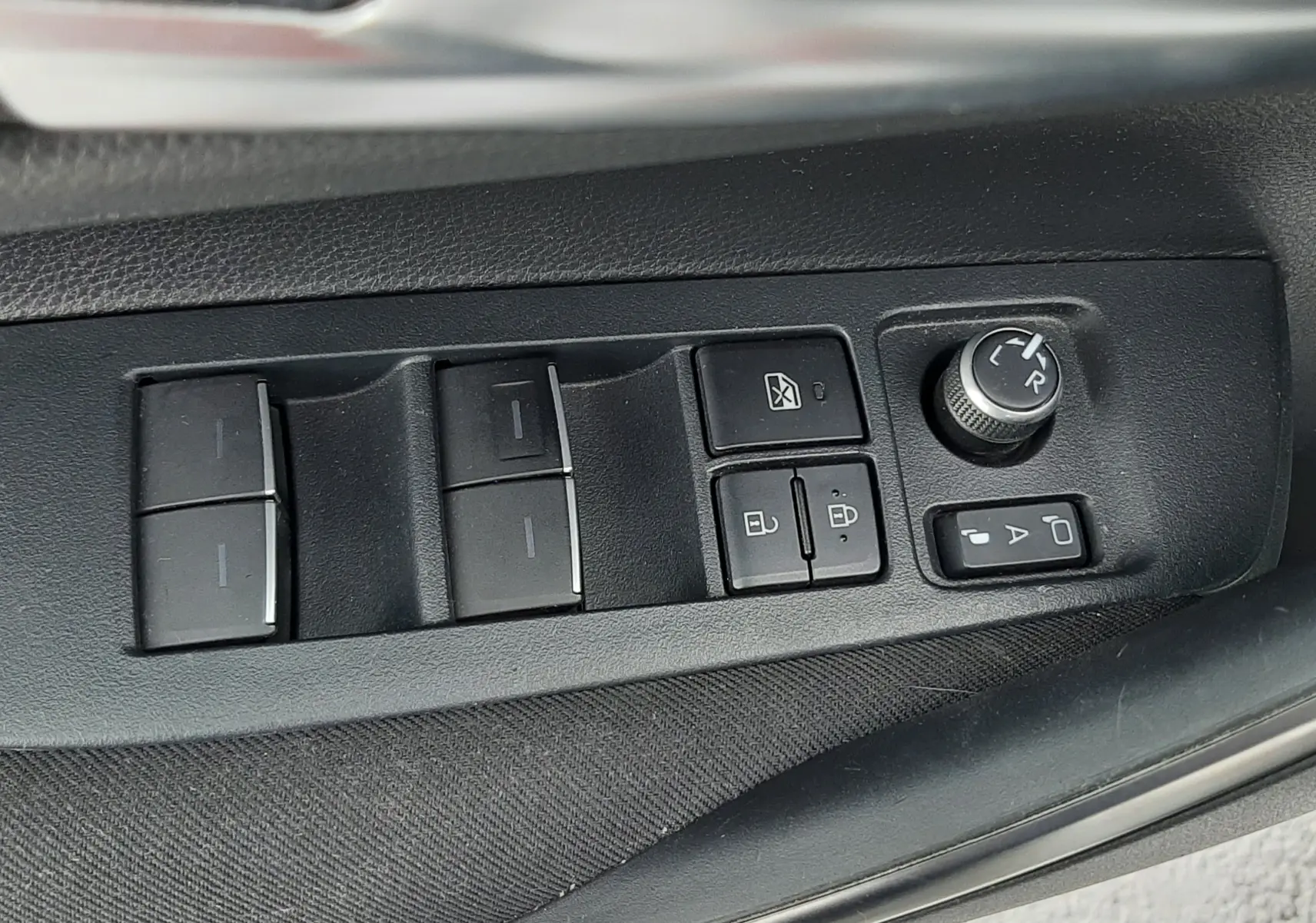 Panneau de commande des vitres et rétroviseurs côté conducteur de la Toyota Corolla blanche 2022 en gros plan.