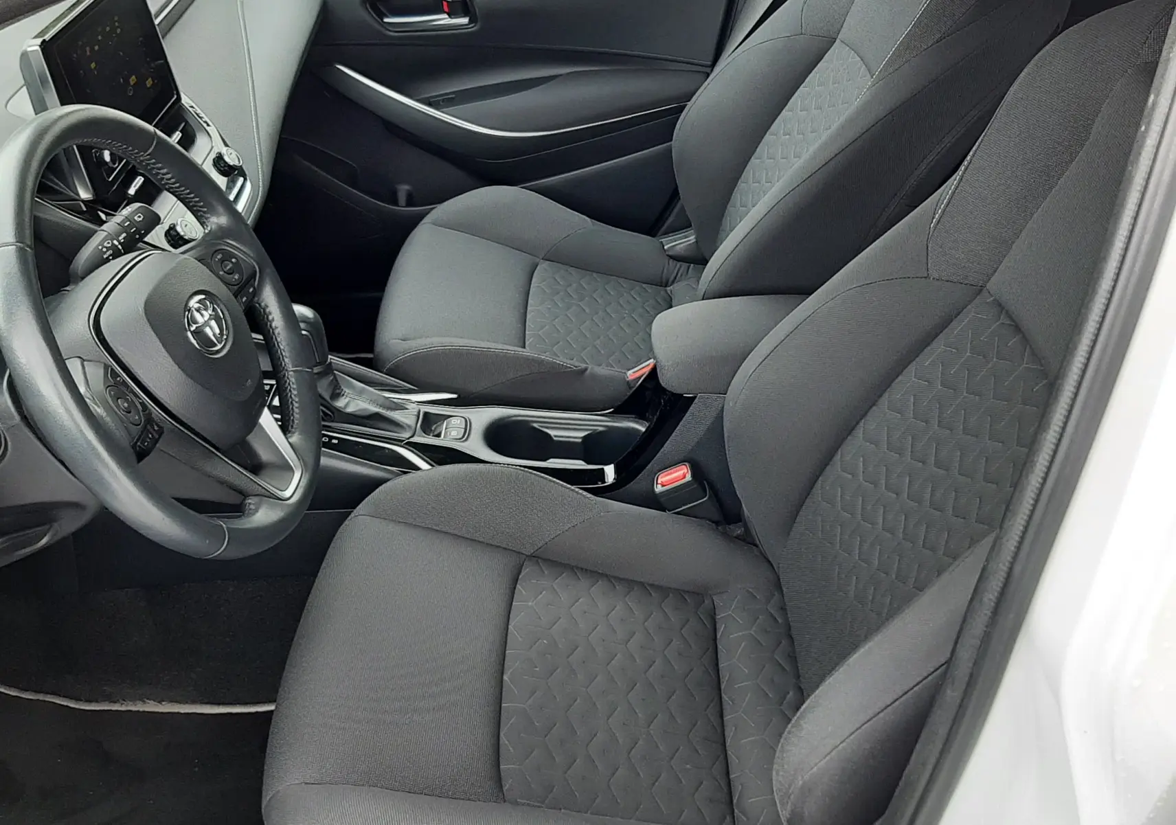 Intérieur de la Toyota Corolla 122 CH DYNAMIC 2022 vue côté conducteur, sièges tissu gris et tableau de bord moderne.