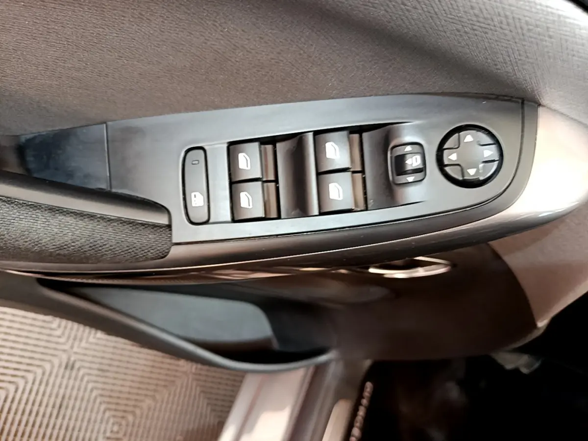 Gros plan sur les commandes de lève-vitres et réglage des rétroviseurs côté conducteur du Citroën Grand C4 SpaceTourer gris foncé.