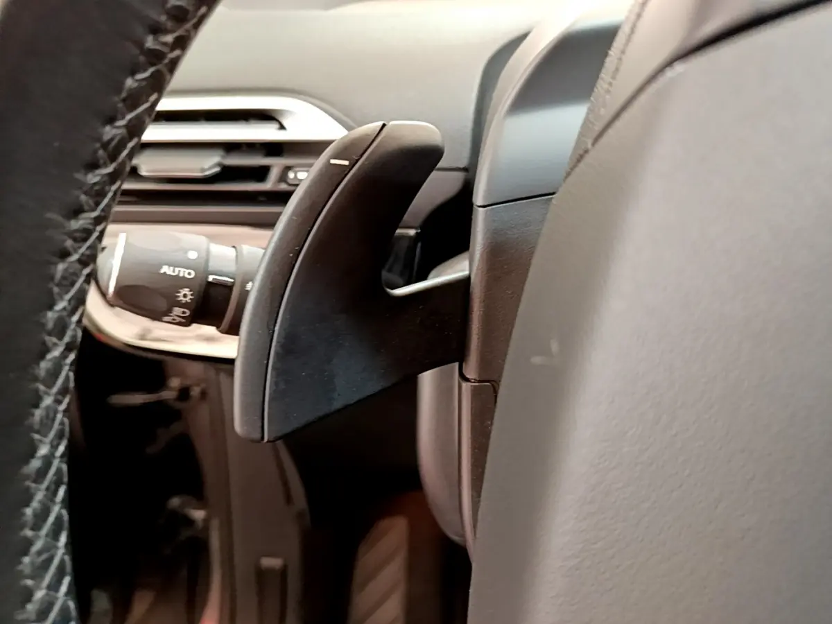 Gros plan sur la palette de changement de vitesse derrière le volant cuir du Citroën Grand C4 SpaceTourer gris foncé.