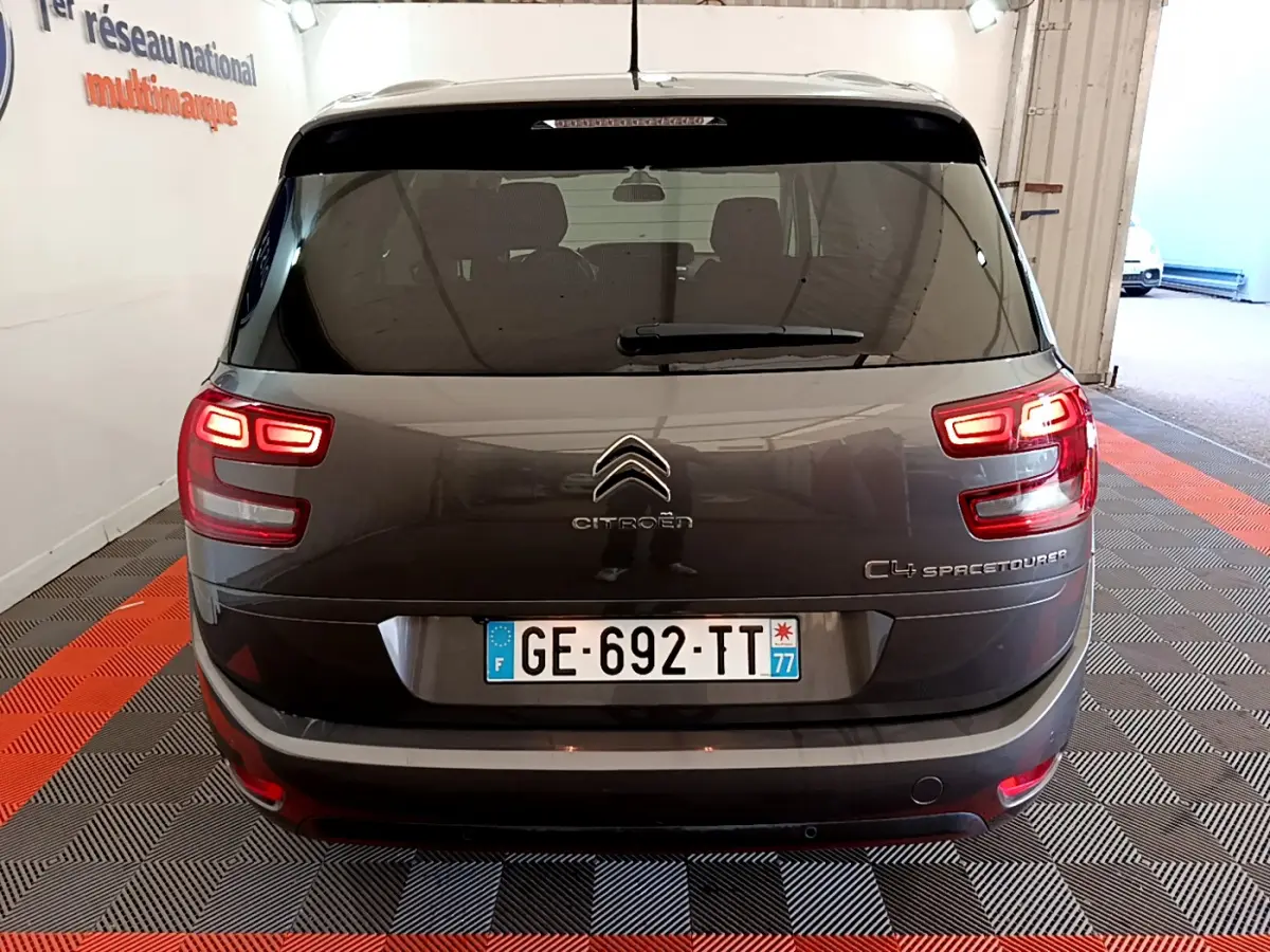 Vue arrière d'un Citroën Grand C4 Spacetourer gris foncé avec feux allumés dans un garage fermé.
