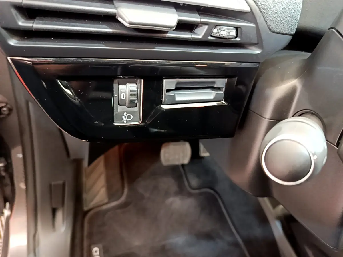 Détail du tableau de bord côté gauche du Citroën Grand C4 Spacetourer gris foncé avec réglage des phares et pédales visibles.