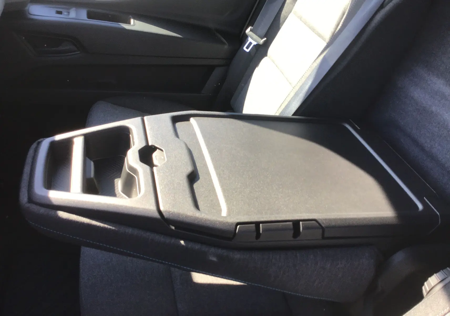 Vue rapprochée de la banquette passager grise avec bureau mobile déployé dans le Renault Master blanc 2025.