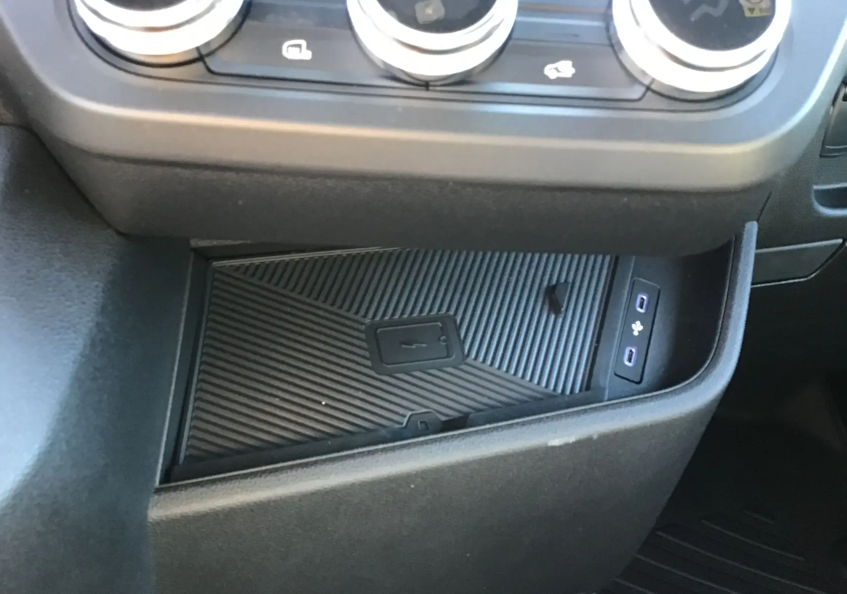 Gros plan sur la console centrale noire du Renault Master blanc, montrant un chargeur sans fil et deux ports USB.