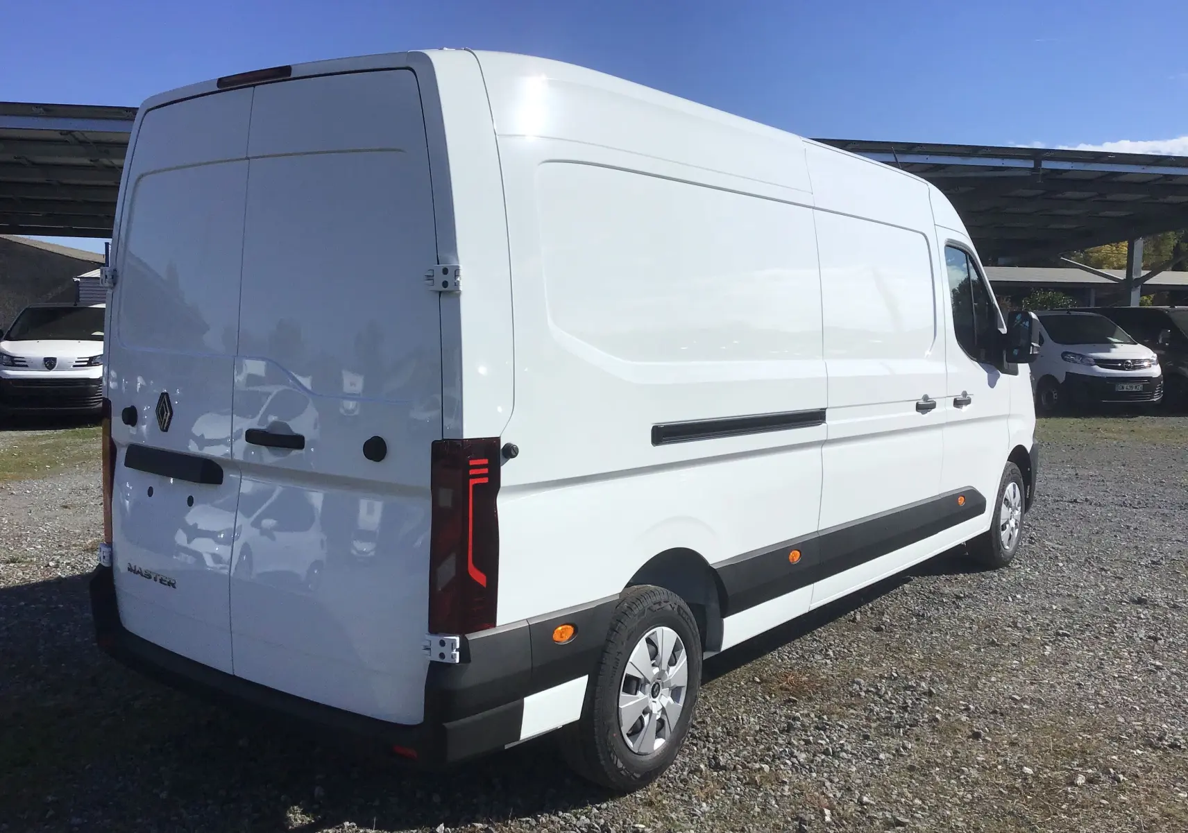 Vue 3/4 arrière droite d’un fourgon Renault Master blanc, avec feux arrière LED et protections latérales noires.