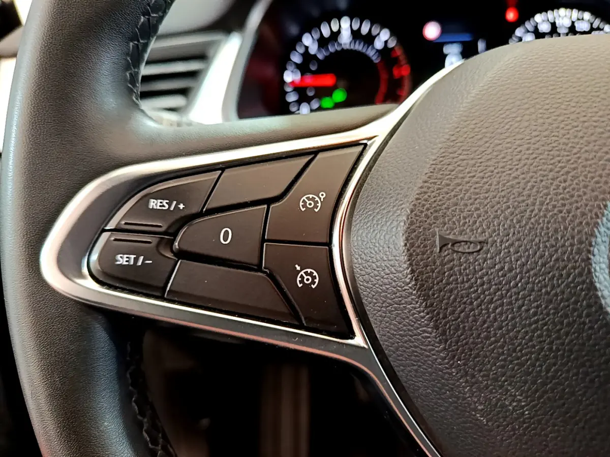 Gros plan sur les commandes du régulateur de vitesse au volant noir du Renault Captur Business Blue dCi 95 2020.