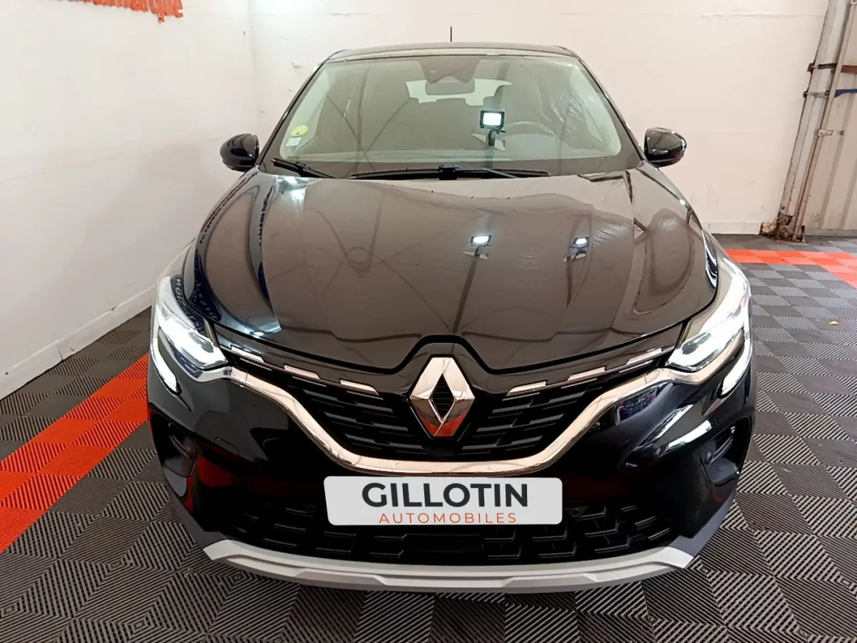 Vue avant rapprochée du Renault Captur noir, mettant en valeur sa calandre chromée et ses phares LED allumés.
