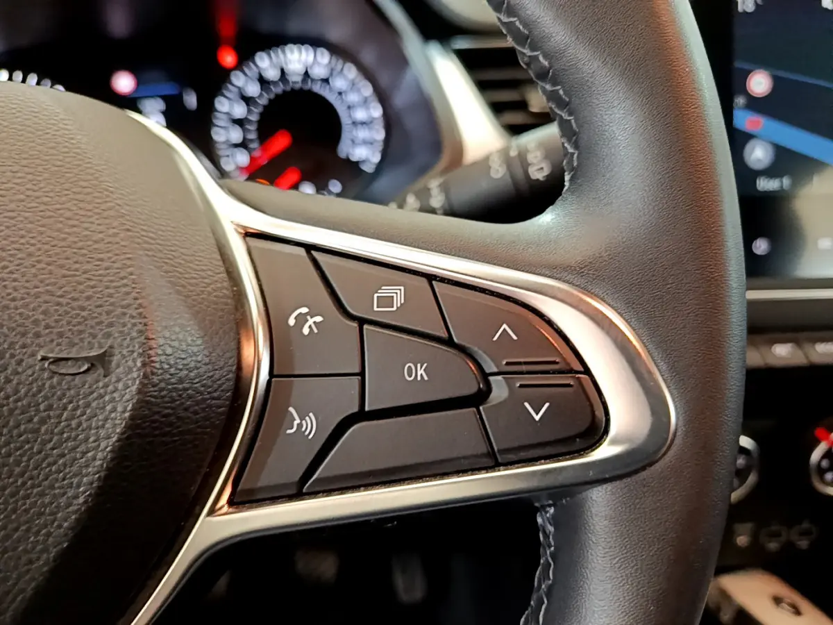 Gros plan sur les commandes au volant noir du Renault Captur 2020, avec tableau de bord et écran tactile en arrière-plan.