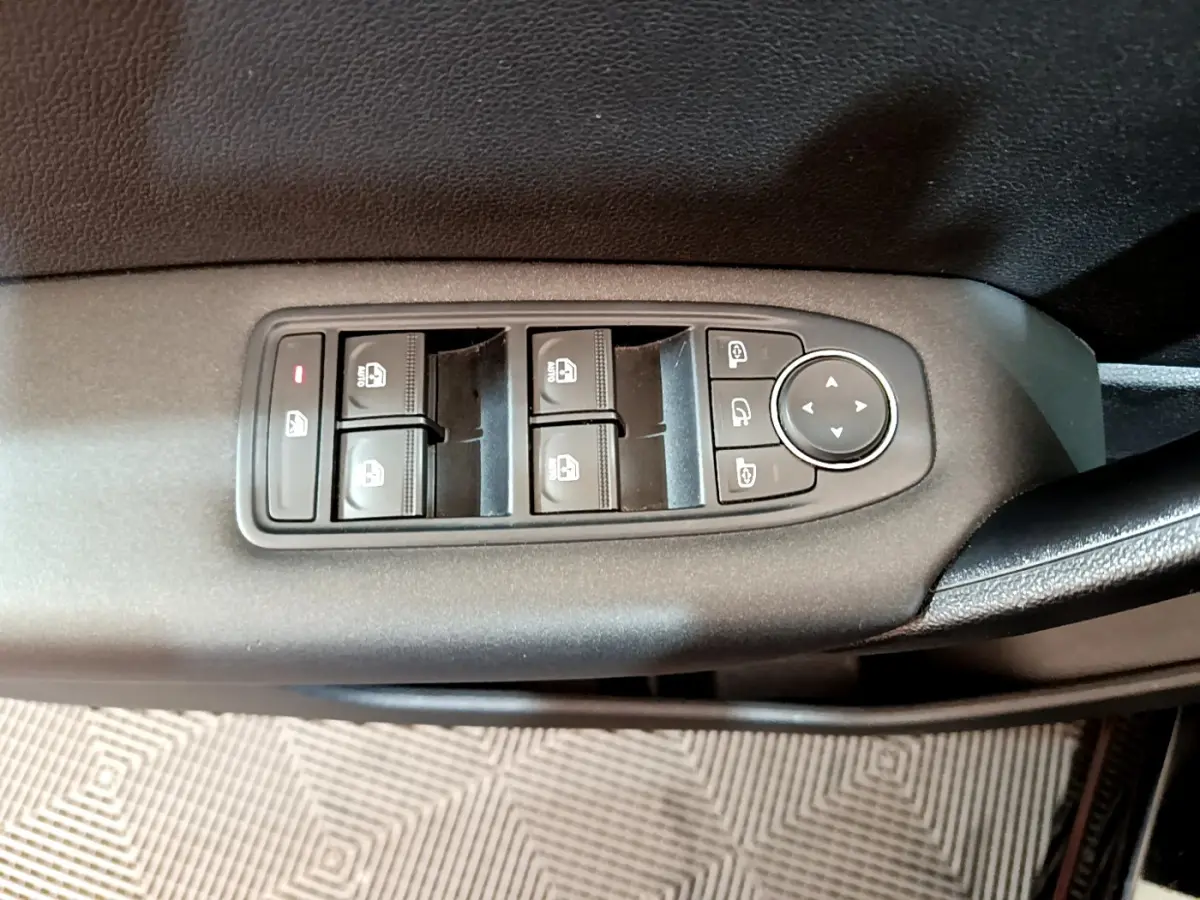 Vue rapprochée des commandes de lève-vitres et rétroviseurs sur la porte intérieure côté conducteur d’un Renault Captur noir.