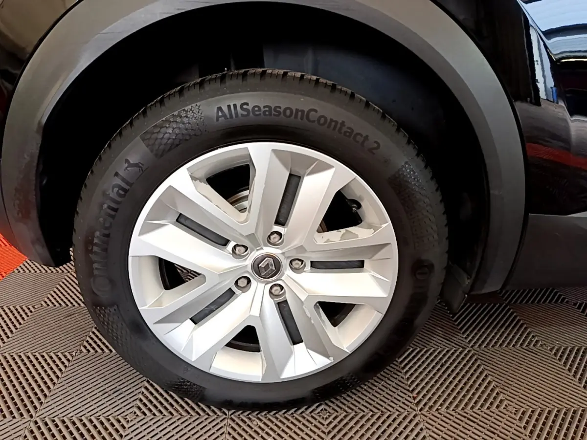Gros plan sur la roue avant droite du Renault Captur noir, mettant en valeur la jante argentée et le pneu Continental AllSeasonContact.