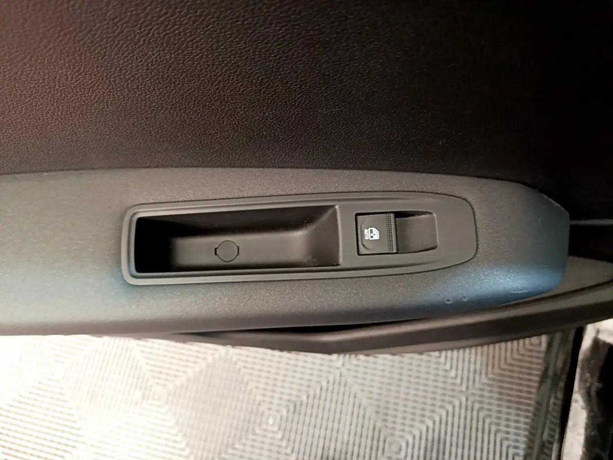 Gros plan sur le bouton de verrouillage centralisé noir sur la porte intérieure côté conducteur d’un Renault Captur noir.