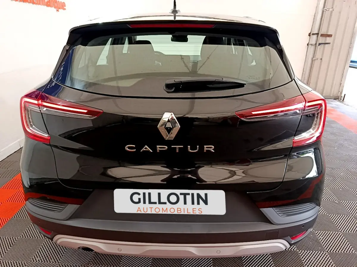 Vue arrière d'un Renault Captur noir avec feux LED allumés et logo central visible dans un garage.