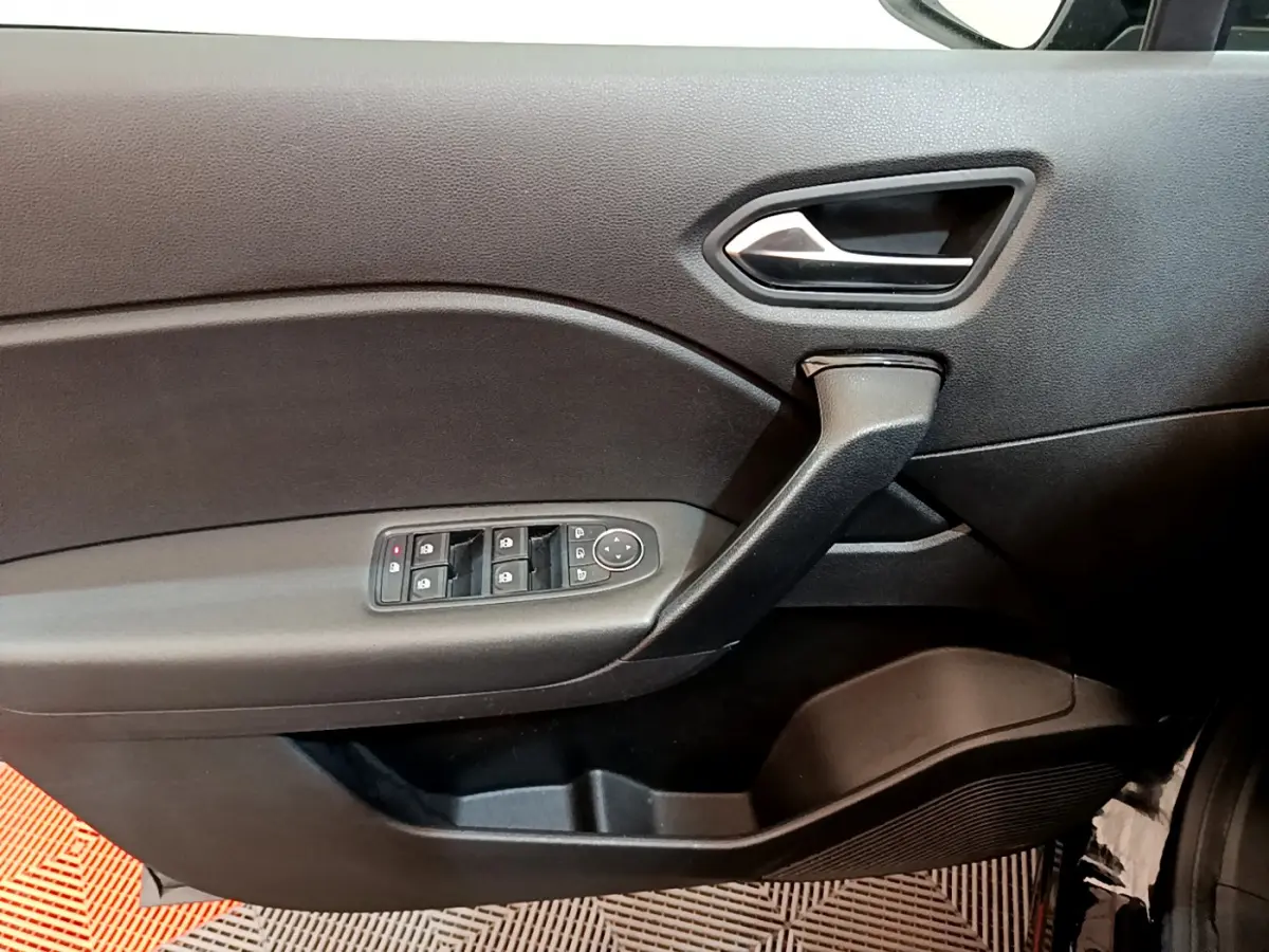 Vue intérieure du panneau de porte côté conducteur noir du Renault Captur Business Blue dCi 95 avec commandes de vitres et rétroviseurs.
