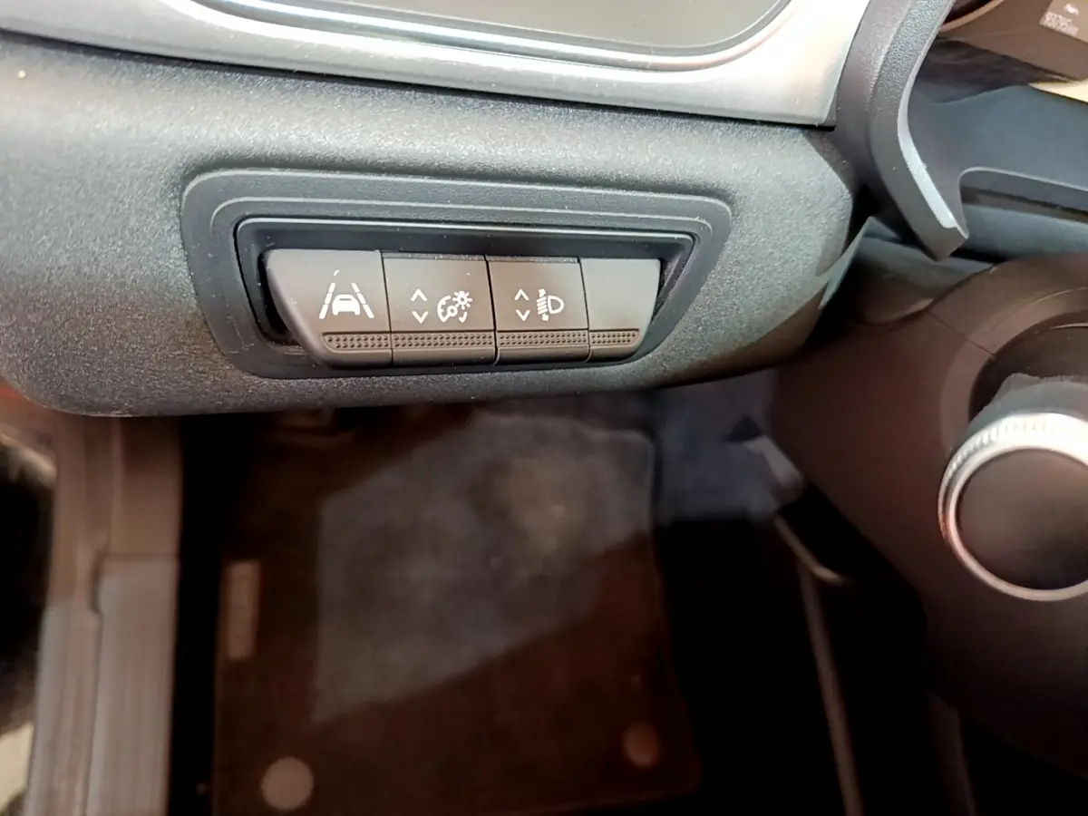 Gros plan sur les boutons de réglage d'assistance et phares du tableau de bord du Renault Captur Business noir de 2020.