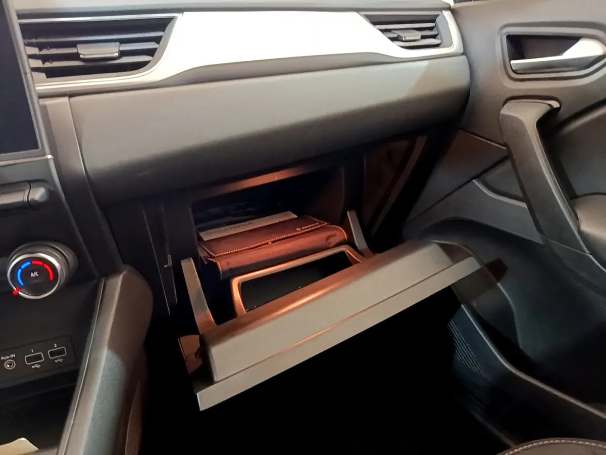 Vue intérieure côté passager du tableau de bord noir du Renault Captur 2020 avec boîte à gants ouverte.