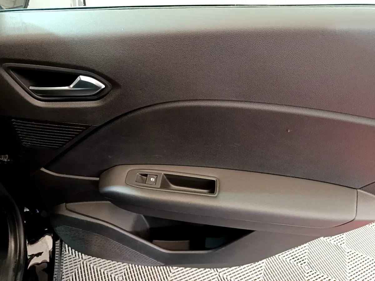 Vue intérieure du panneau de porte côté conducteur du Renault Captur noir, avec poignée argentée et commande de fenêtre.