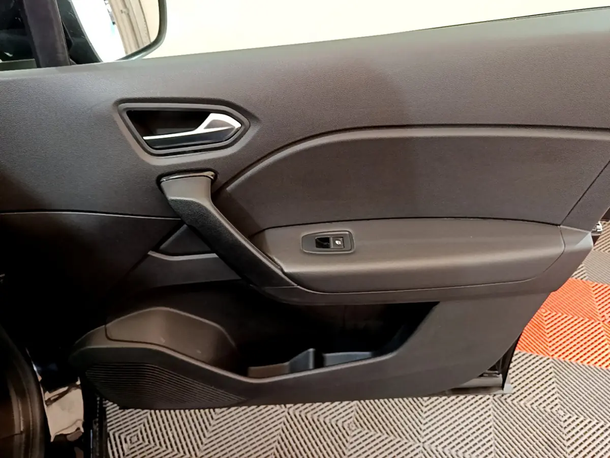 Vue rapprochée de la porte intérieure côté gauche noire du Renault Captur Business Blue dCi 95 avec poignée et commande de vitre.