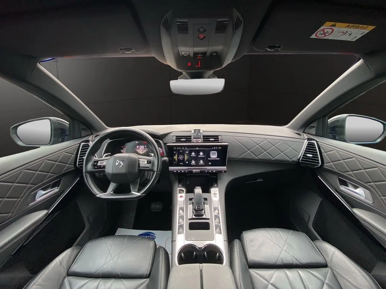 Vue intérieure avant du DS7 2024 avec sellerie cuir noir électrique et tableau de bord matelassé élégant.