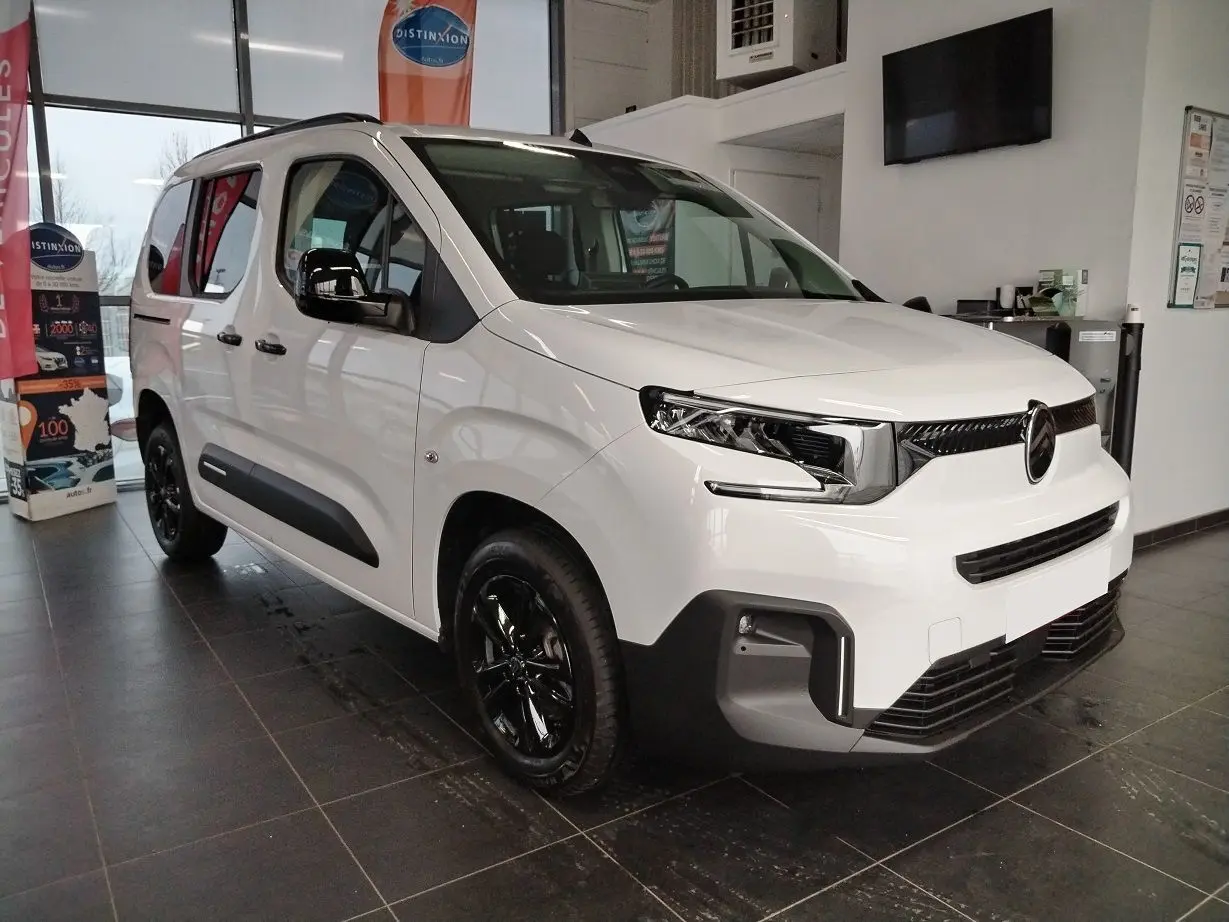 Citroën Berlingo blanc vue 3/4 avant droit en intérieur, avec jantes alu noir Starlit et rails latéraux couleur carrosserie.