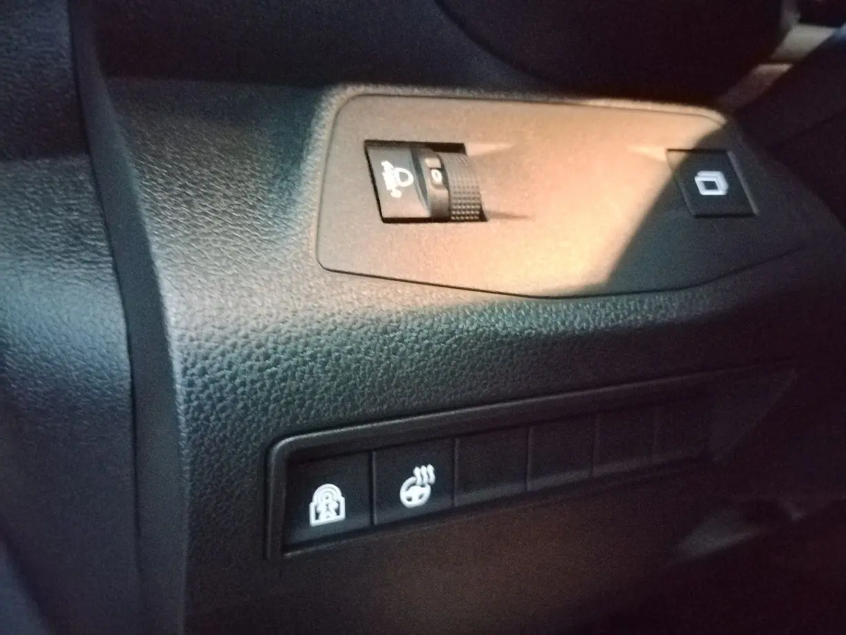 Gros plan sur les commandes intérieures du tableau de bord du Citroën Berlingo blanc, avec réglage des phares et sièges chauffants.