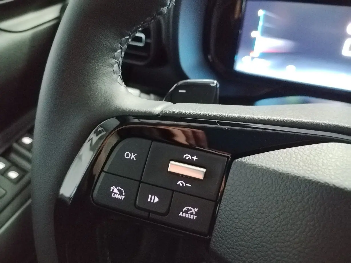 Gros plan sur les commandes noires au volant du Citroën Berlingo blanc, avec touches de régulateur et assistant de conduite.