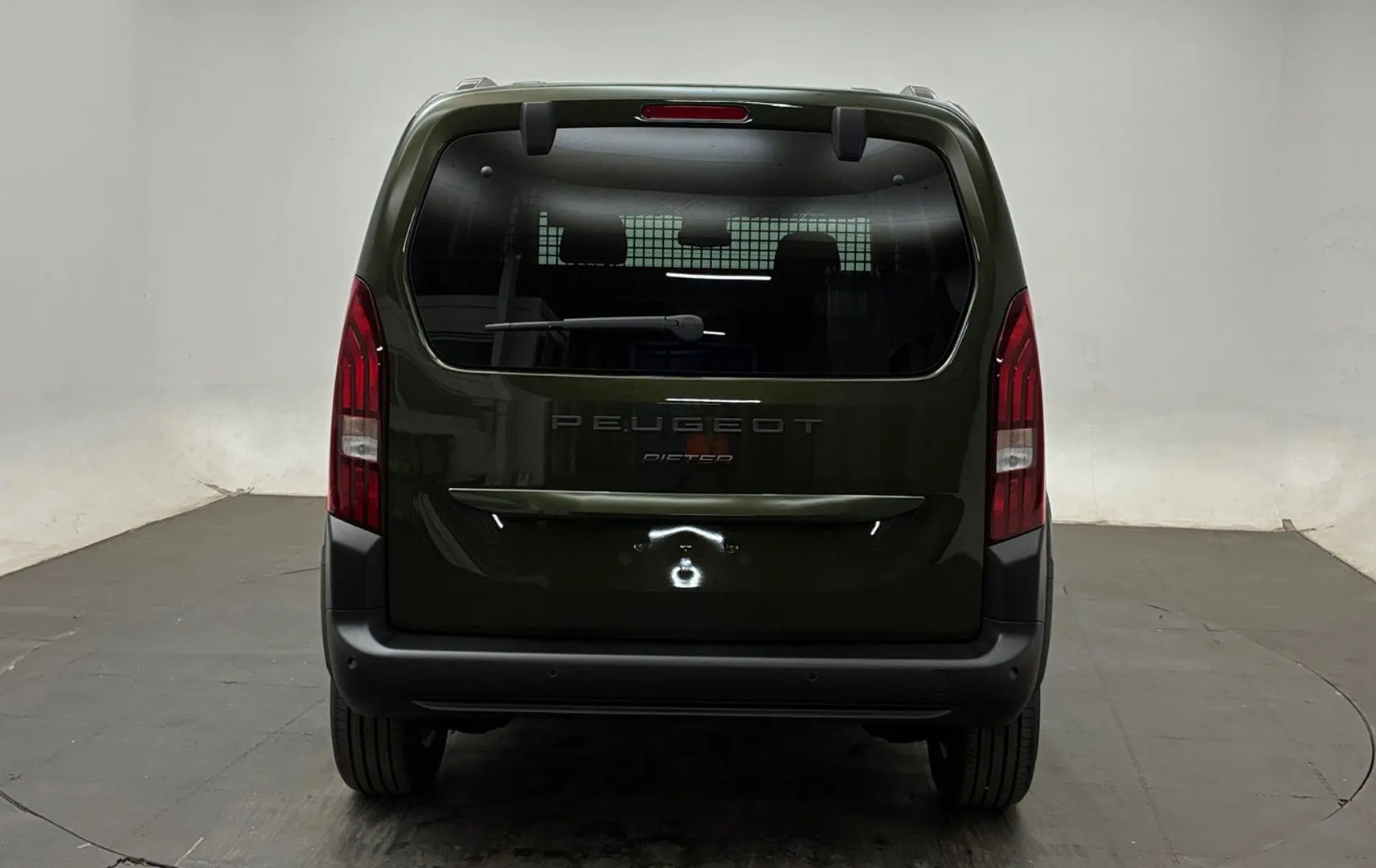Vue arrière d'un Peugeot Rifter 2026 vert Sirkka avec hayon vitré et pare-chocs noir mat dans un studio.
