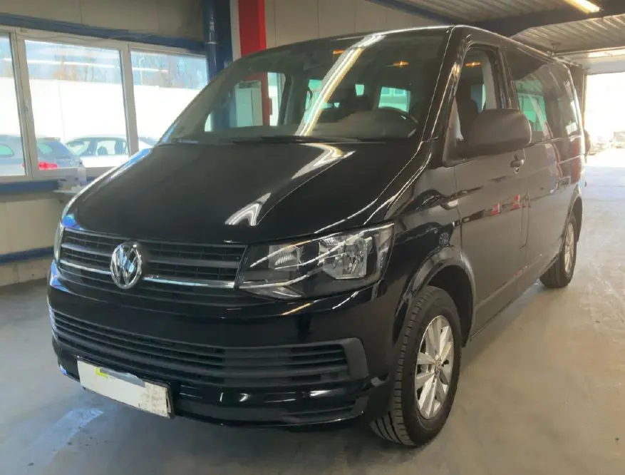 Volkswagen Multivan T6 noir vu en 3/4 avant droit dans un garage avec calandre et phares nets.