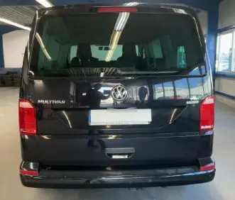 Vue arrière d’un Volkswagen Multivan T6 noir, version Trendline 2015, dans un garage lumineux.