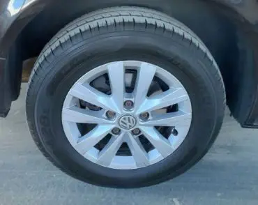 Gros plan sur la roue avant droite du Volkswagen Multivan T6 noir, jante alliage avec logo VW central visible.