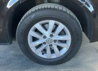 Gros plan sur la roue avant droite d’un Volkswagen Multivan noir T6 PH.1 avec jante alliage argentée.