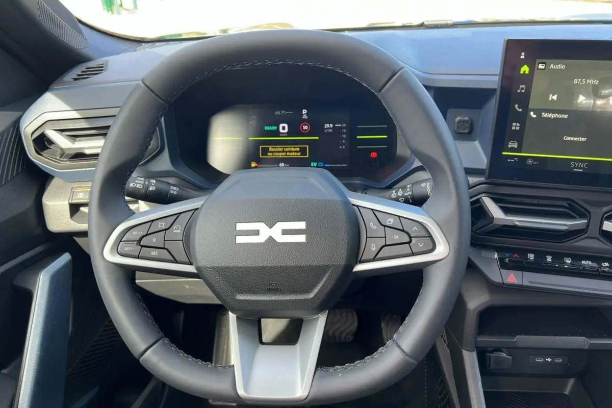 Vue rapprochée du volant cuir noir et du tableau de bord numérique du Dacia Bigster Hybrid 155 Expression Plus.