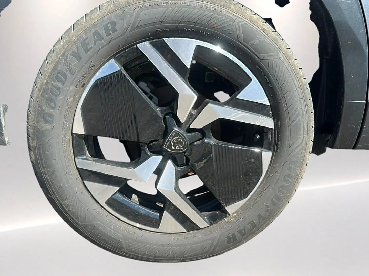 Gros plan sur la jante alu bicolore noire et argentée du côté gauche d’un Peugeot 2008 gris Artense.
