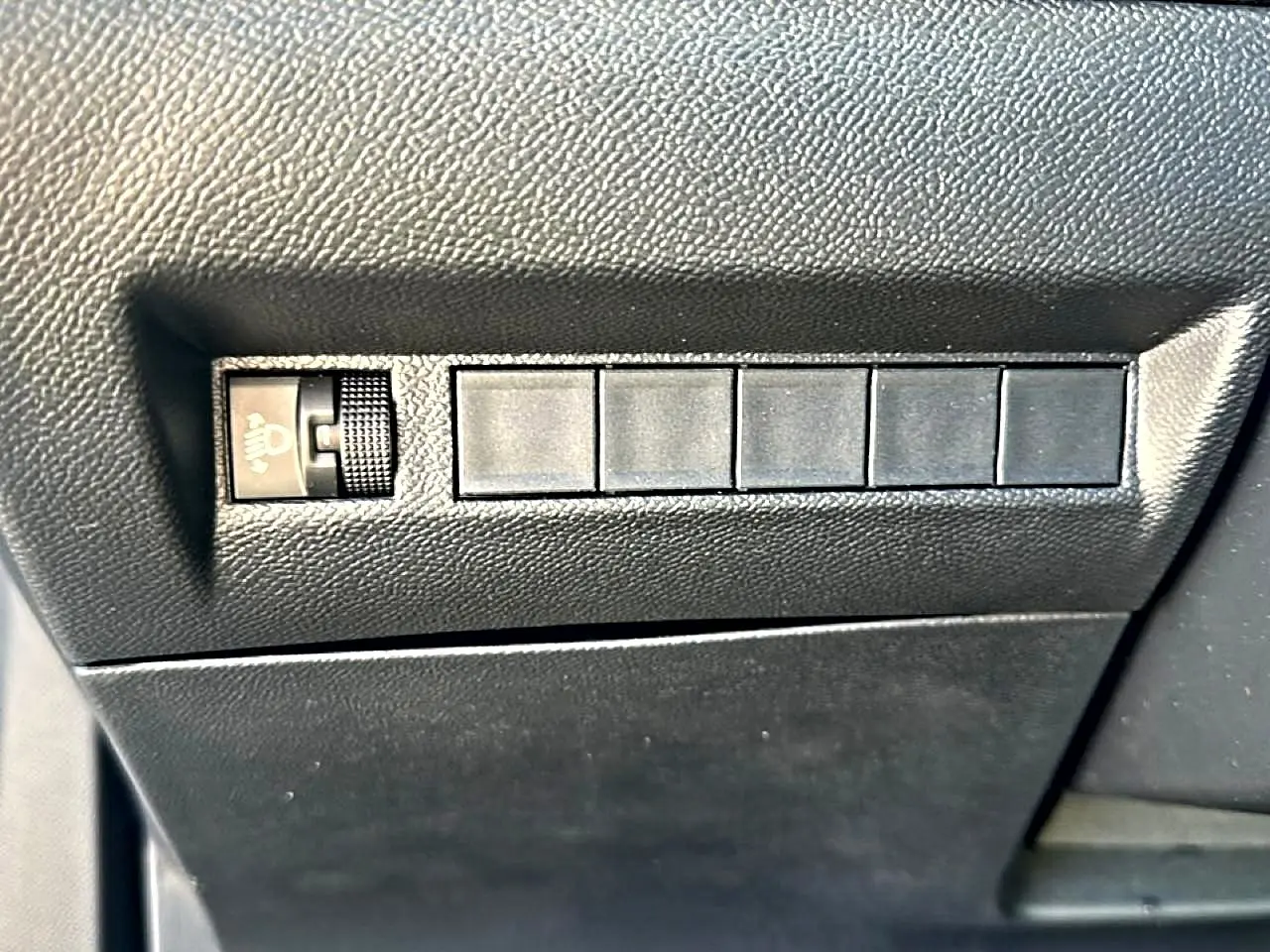 Gros plan sur le tableau de bord côté conducteur du Peugeot 2008 gris Artense, avec molette de réglage des phares.