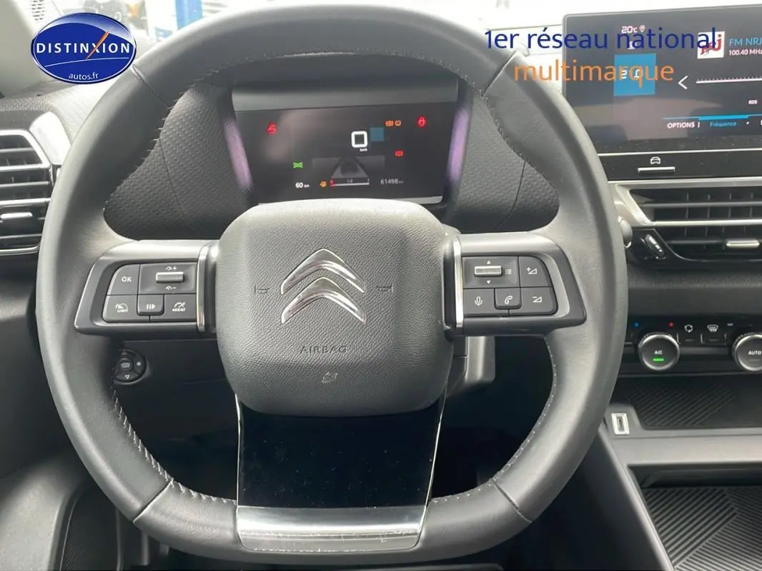 Vue rapprochée du volant cuir noir de la Citroën C4 2022 avec commandes intégrées et tableau de bord numérique.