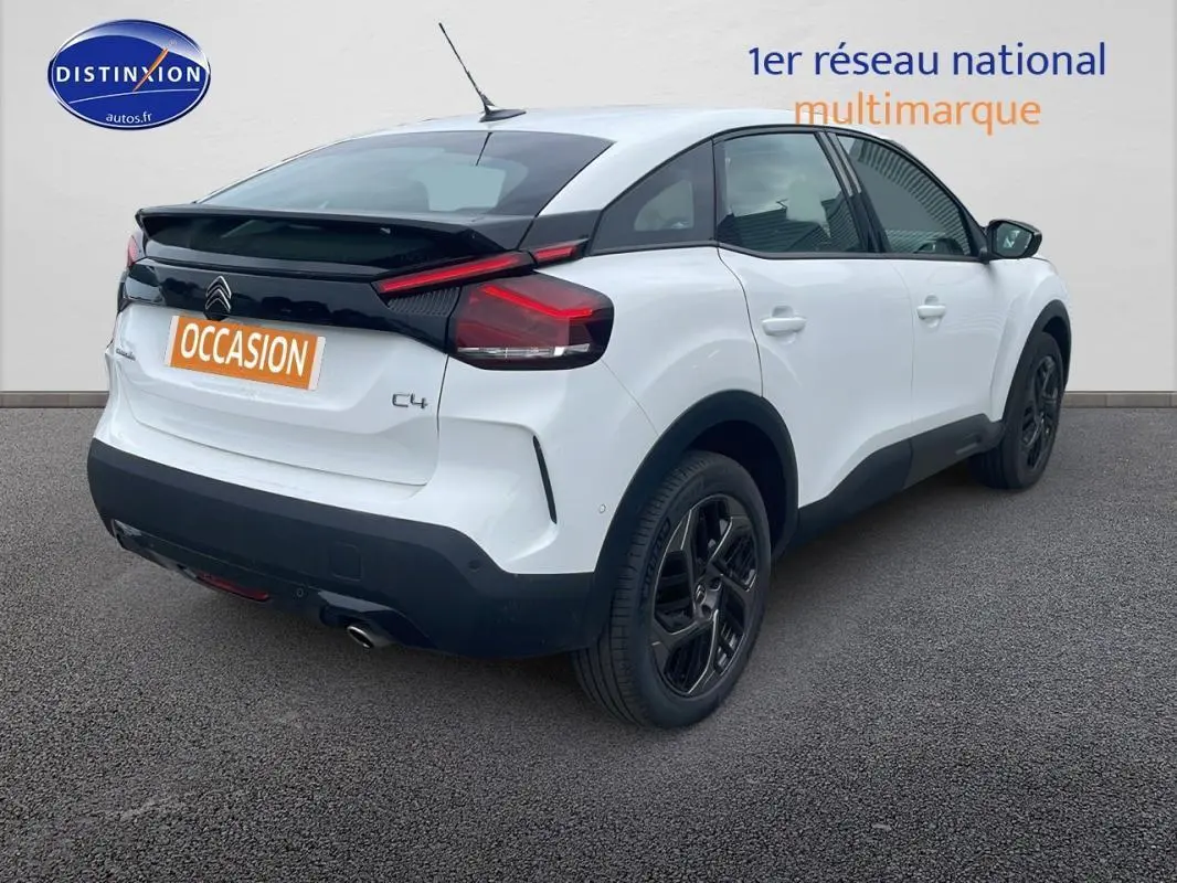 Vue 3/4 arrière droite d'une Citroën C4 blanche avec jantes alliage noires et feux arrière distinctifs.