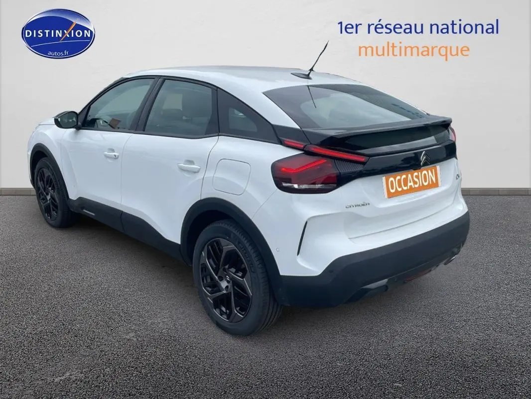 Vue 3/4 arrière droite d'une Citroën C4 blanche 2022 avec jantes alliage noires et bandeau noir arrière.