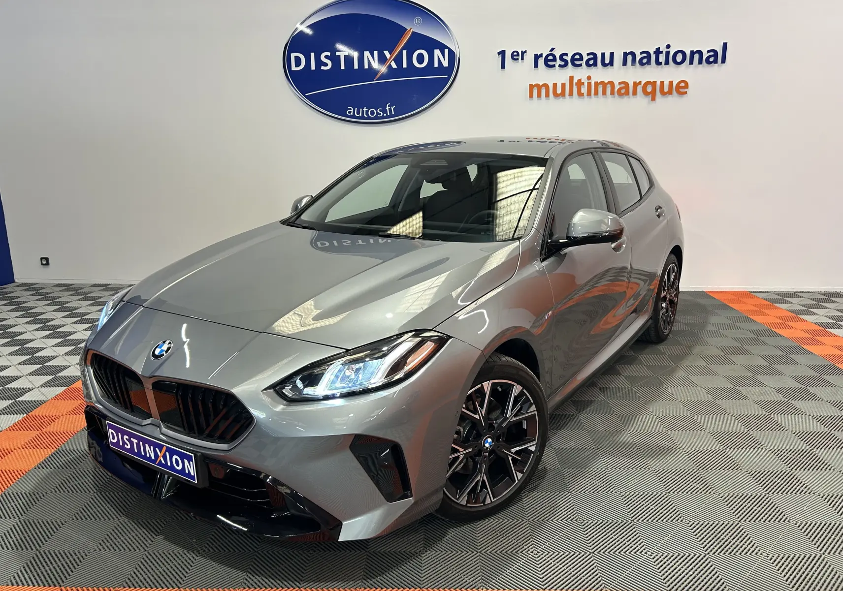 BMW Série 1 120DA M Sport gris Skyscrap vue 3/4 avant droit avec phares LED allumés en intérieur showroom