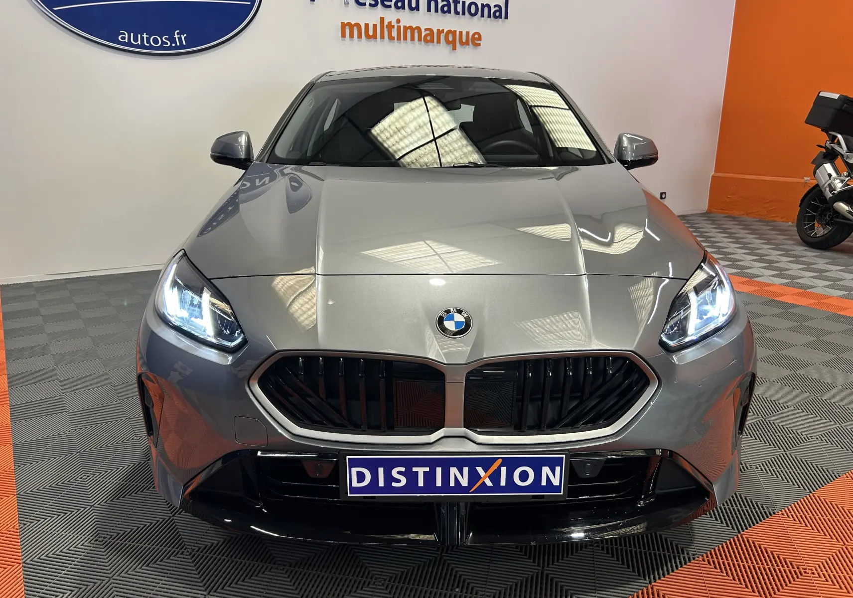 Vue frontale d'une BMW Série 1 120DA M Sport gris Skyscrap avec phares LED allumés et calandre noire sportive.