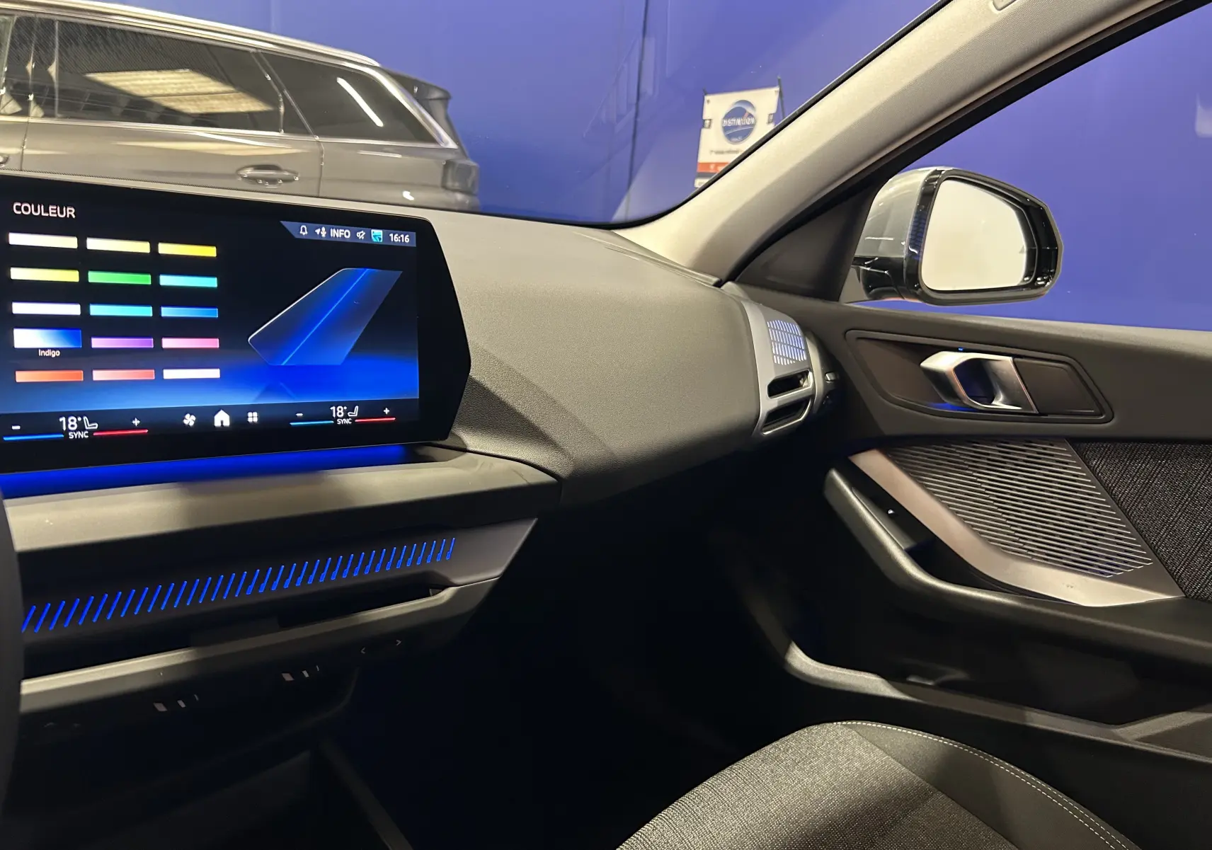 Intérieur avant droit de la BMW Série 1 120DA gris Skyscrap avec écran tactile et éclairage d'ambiance bleu.