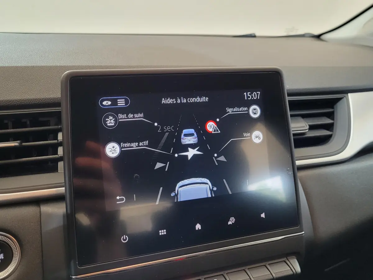 Écran tactile central du tableau de bord du Renault Captur Business gris clair montrant les aides à la conduite.