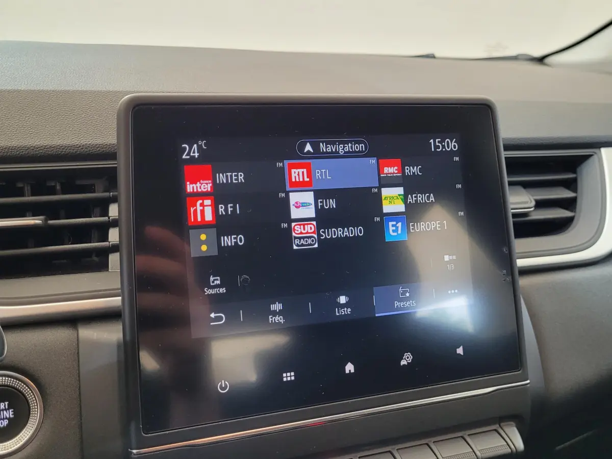 Écran tactile central du tableau de bord du Renault Captur gris clair, affichant les stations radio FM.