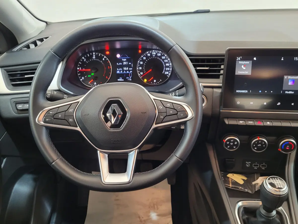 Vue intérieure frontale du tableau de bord du Renault Captur Business gris clair avec volant multifonctions et écran tactile.