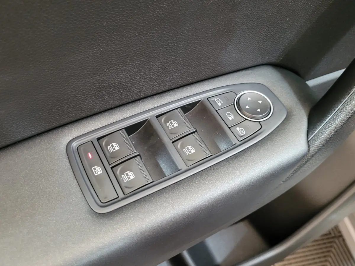 Gros plan sur les commandes de lève-vitres et rétroviseurs électriques côté conducteur du Renault Captur gris clair 2021.