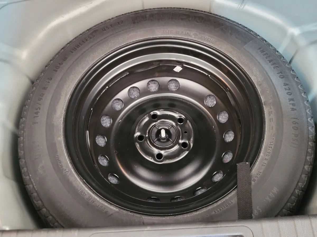 Gros plan sur la roue de secours noire dans le coffre d'un Renault Captur gris clair Business Blue dCi 95 2021.